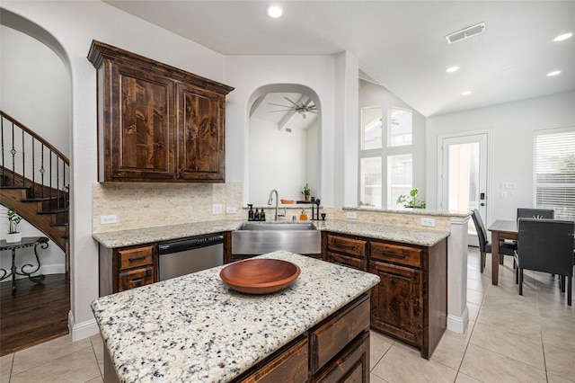 kitchen with tasteful backsplash, visible vents, arched walkways, stainless steel dishwasher, and a sink