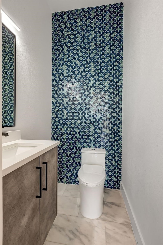 bathroom featuring marble finish floor, baseboards, vanity, and toilet