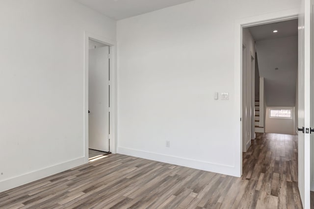 spare room with stairway, baseboards, and wood finished floors