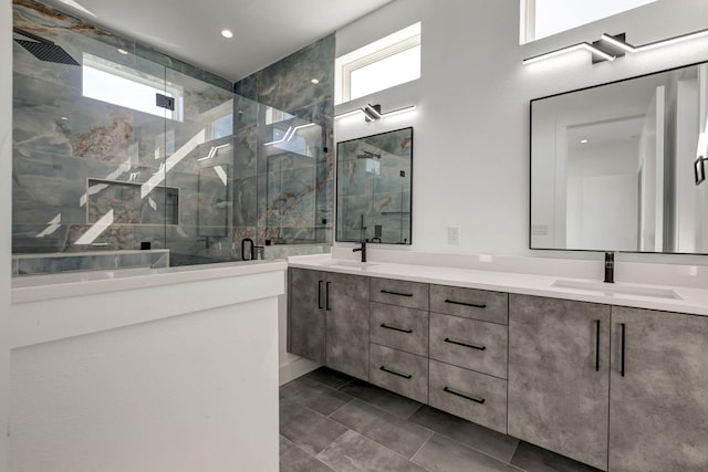 bathroom with double vanity, a shower stall, a sink, and tile patterned floors