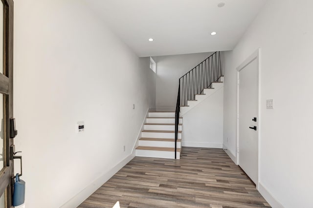 foyer featuring recessed lighting, wood finished floors, baseboards, and stairs