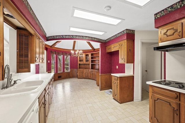 kitchen featuring black electric cooktop, under cabinet range hood, a sink, light countertops, and an inviting chandelier