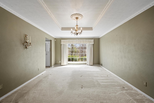 carpeted spare room featuring a tray ceiling, crown molding, a notable chandelier, a textured wall, and baseboards