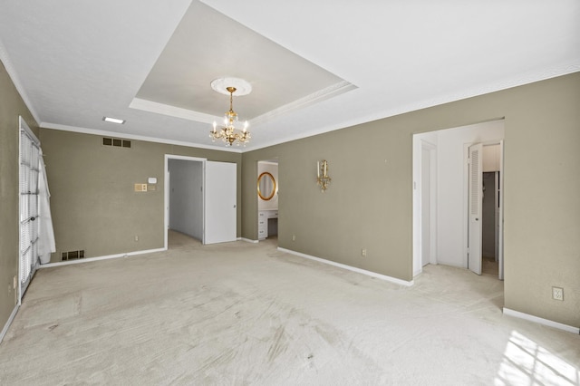 unfurnished room with a chandelier, a raised ceiling, visible vents, and baseboards