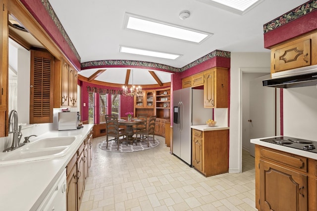 kitchen with light countertops, stainless steel fridge, a sink, and a notable chandelier