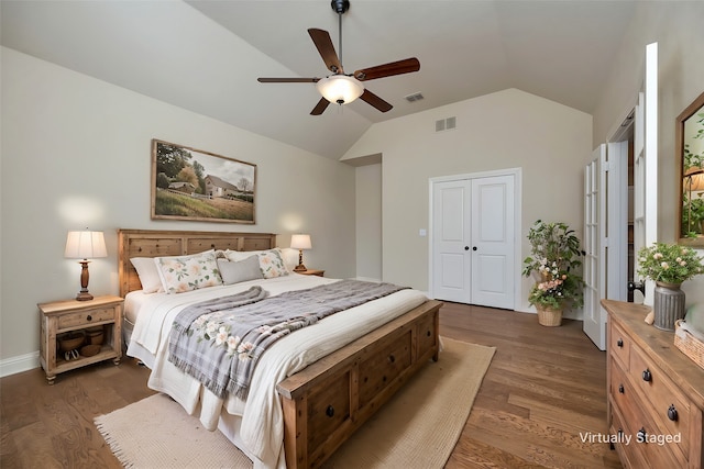 bedroom with a closet, visible vents, lofted ceiling, and dark wood-style flooring