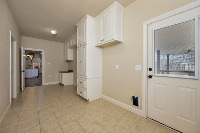 clothes washing area with light tile patterned floors, a chandelier, and baseboards