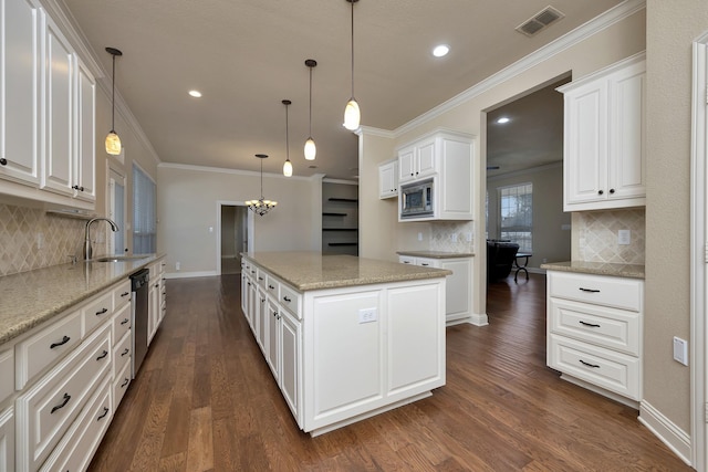 kitchen with ornamental molding, appliances with stainless steel finishes, a kitchen island, and a sink