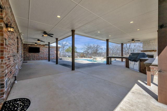 view of patio featuring exterior kitchen, a ceiling fan, an outdoor pool, and a grill