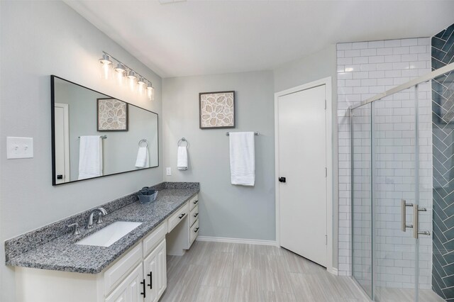 bathroom with baseboards, vanity, and a shower stall