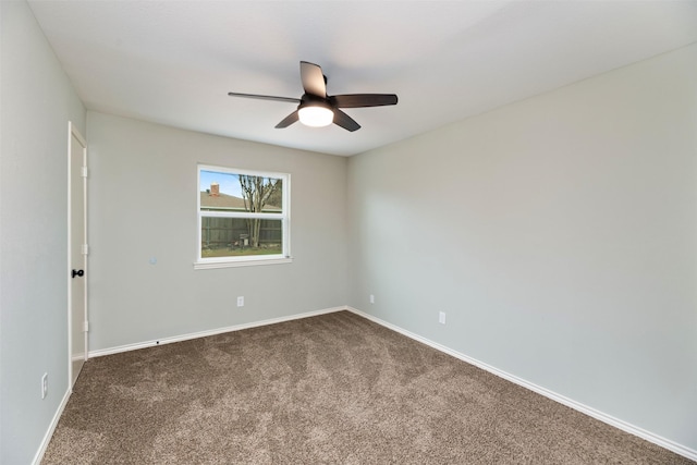 spare room featuring baseboards, dark carpet, and ceiling fan