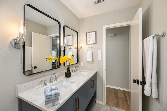 bathroom featuring double vanity, wood finished floors, a sink, and visible vents