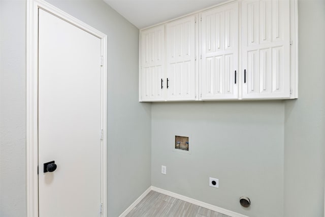 clothes washing area featuring cabinet space, baseboards, light wood-style flooring, hookup for a washing machine, and hookup for an electric dryer