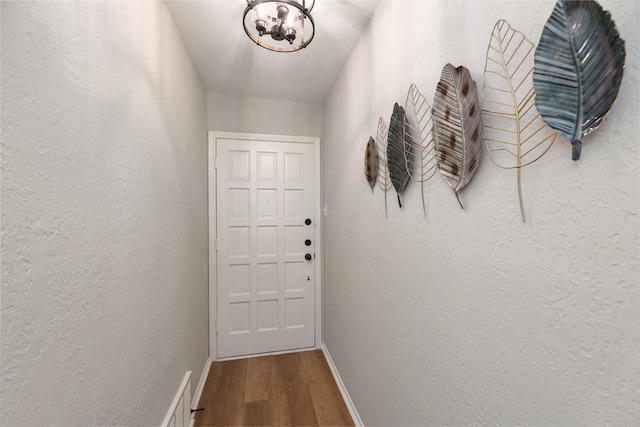 entryway with visible vents, a textured wall, baseboards, and wood finished floors