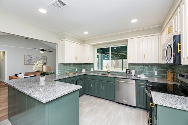 kitchen with visible vents, white cabinets, appliances with stainless steel finishes, a peninsula, and a sink