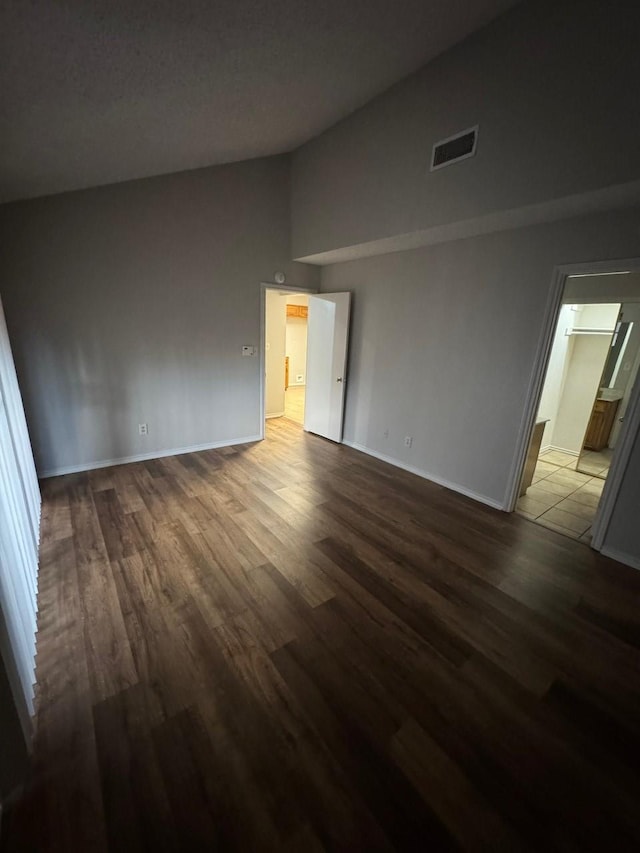 unfurnished bedroom with visible vents, baseboards, wood finished floors, and vaulted ceiling