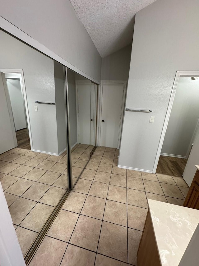 bathroom with tile patterned flooring, lofted ceiling, and a textured ceiling