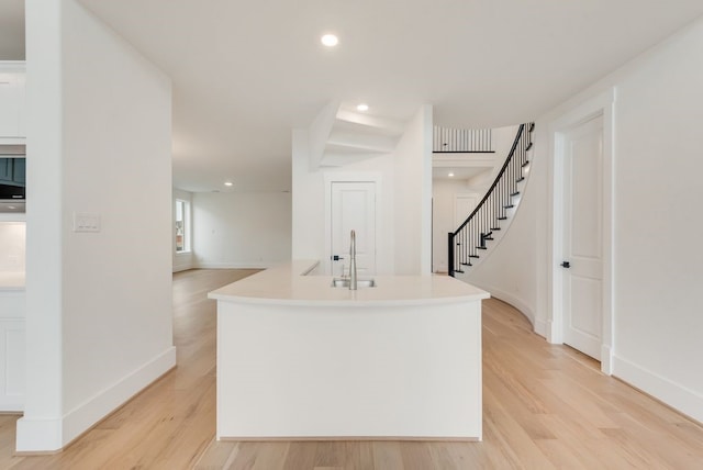 kitchen with recessed lighting, a sink, baseboards, light countertops, and light wood-type flooring