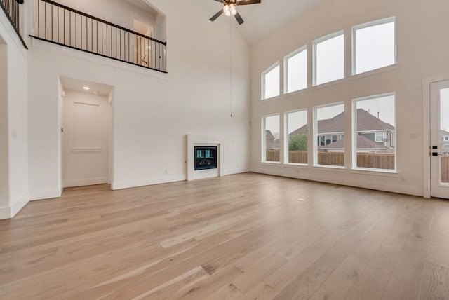 1813 Cousins Trl, Frisco, TX 75034 - unfurnished living room featuring high vaulted ceiling, ceiling fan, light wood-style floors, baseboards, and a glass covered fireplace