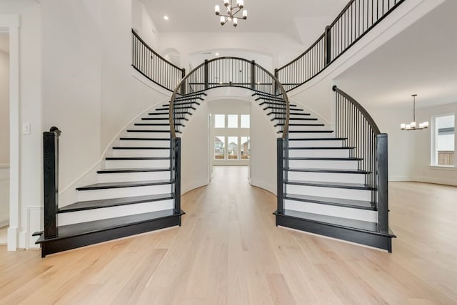 stairs with arched walkways, a notable chandelier, a high ceiling, wood finished floors, and baseboards