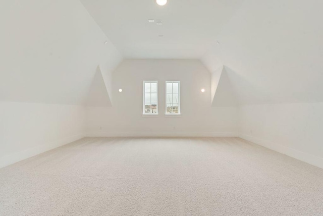 additional living space with carpet, baseboards, and vaulted ceiling