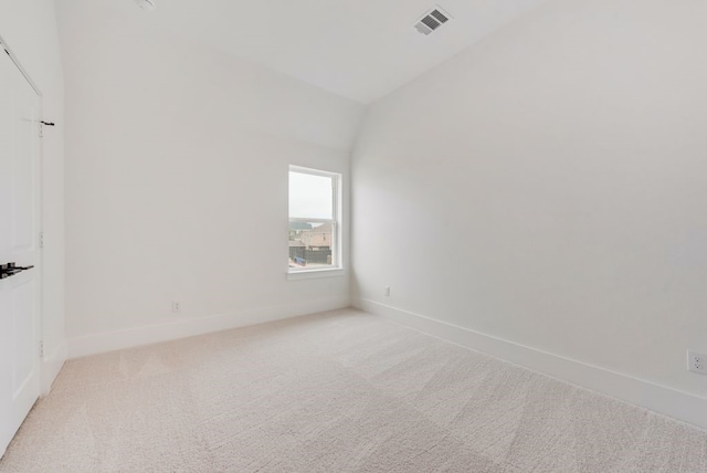 unfurnished room featuring lofted ceiling, baseboards, visible vents, and light colored carpet