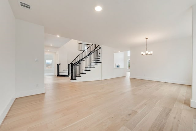 unfurnished living room with a notable chandelier, recessed lighting, visible vents, light wood-style floors, and stairway