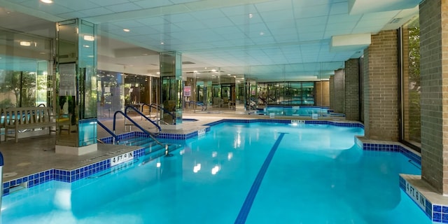 pool with an indoor hot tub and a patio