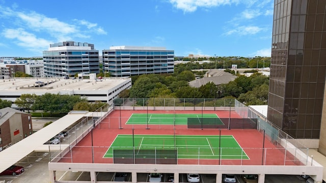 view of tennis court with a view of city and fence