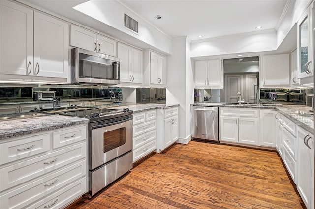 kitchen featuring white cabinets, tasteful backsplash, visible vents, and stainless steel appliances