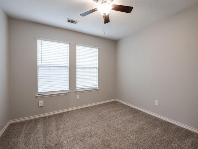 carpeted empty room with a textured ceiling, ceiling fan, visible vents, and baseboards