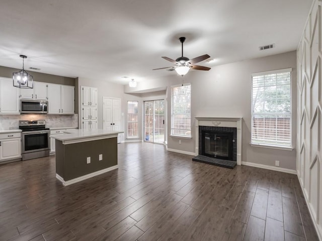 kitchen with a wealth of natural light, visible vents, appliances with stainless steel finishes, a glass covered fireplace, and open floor plan