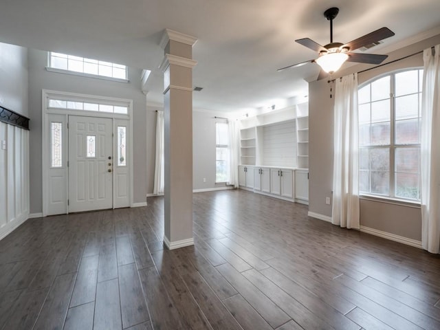 entrance foyer with ornate columns, dark wood finished floors, and a wealth of natural light