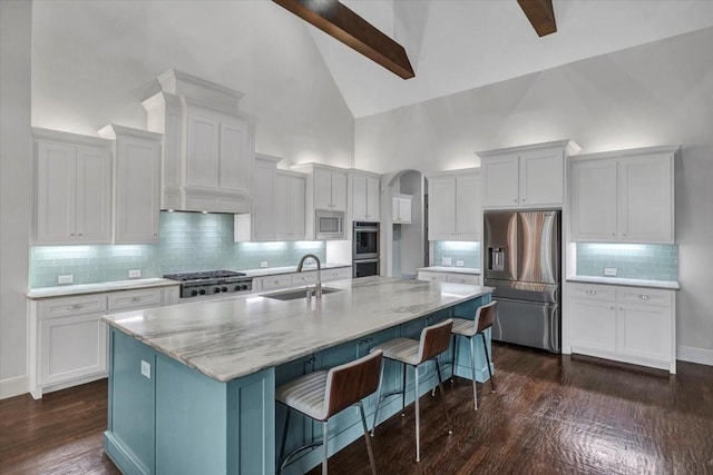 kitchen featuring a sink, a kitchen breakfast bar, appliances with stainless steel finishes, visible vents, and arched walkways