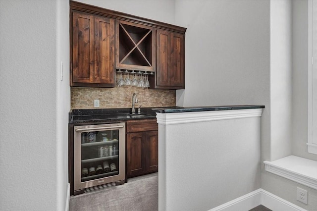 bar featuring decorative backsplash, a sink, beverage cooler, indoor wet bar, and light colored carpet