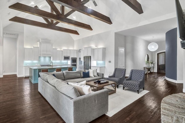 living area featuring a healthy amount of sunlight, dark wood-style floors, beam ceiling, ceiling fan, and a fireplace