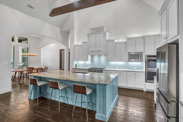 kitchen with a kitchen breakfast bar, a sink, arched walkways, visible vents, and appliances with stainless steel finishes