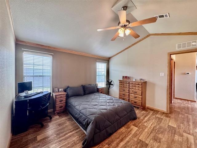 bedroom featuring wood finished floors, visible vents, crown molding, and vaulted ceiling