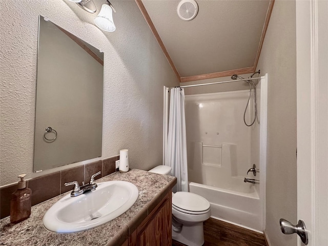 full bathroom with shower / bath combo with shower curtain, toilet, a textured wall, and vanity