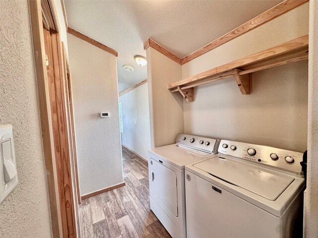 laundry room featuring light wood finished floors, a textured ceiling, washing machine and clothes dryer, and laundry area