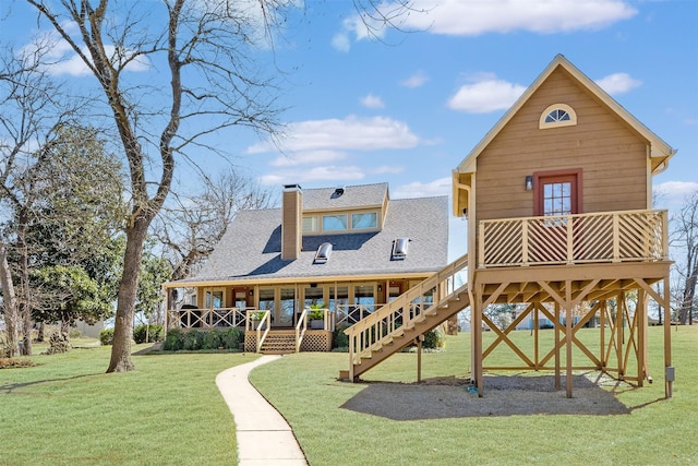 rear view of house featuring stairs, a lawn, roof with shingles, and a chimney