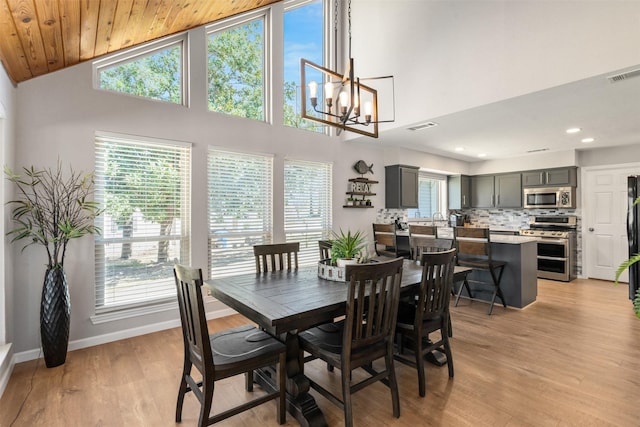 dining area with light wood-type flooring, visible vents, baseboards, and an inviting chandelier