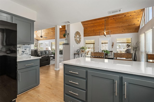 kitchen featuring vaulted ceiling, visible vents, gray cabinets, and freestanding refrigerator