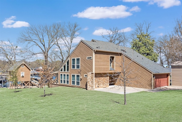 rear view of house with a patio, a lawn, stone siding, and a shingled roof