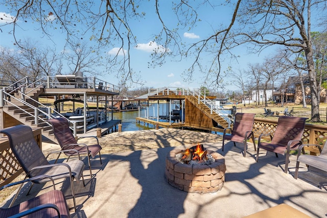 view of patio with a fire pit, stairs, a boat dock, and a water view