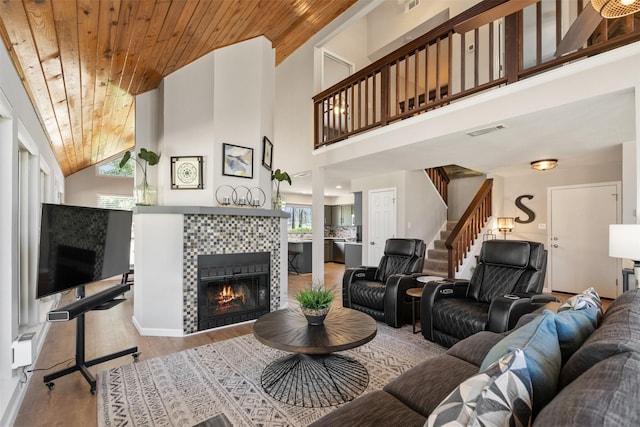 living area featuring visible vents, wood finished floors, wood ceiling, stairs, and a tile fireplace