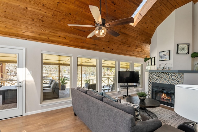 living room featuring a ceiling fan, wood finished floors, lofted ceiling, a tile fireplace, and wood ceiling