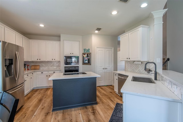 kitchen featuring light wood-type flooring, white cabinets, a sink, and black appliances