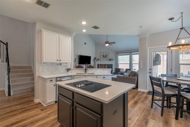 kitchen with black electric stovetop, a sink, visible vents, and white cabinets