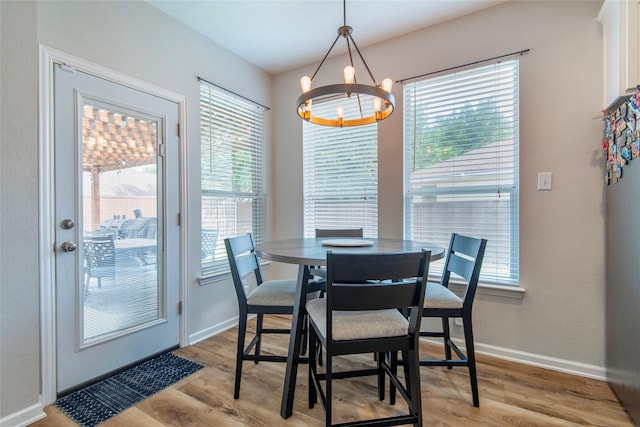 dining room with light wood-style flooring, baseboards, and a notable chandelier